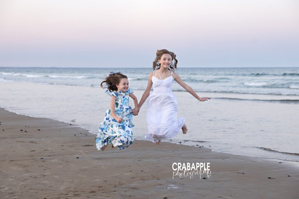 Two sisters jump in the air at the beach