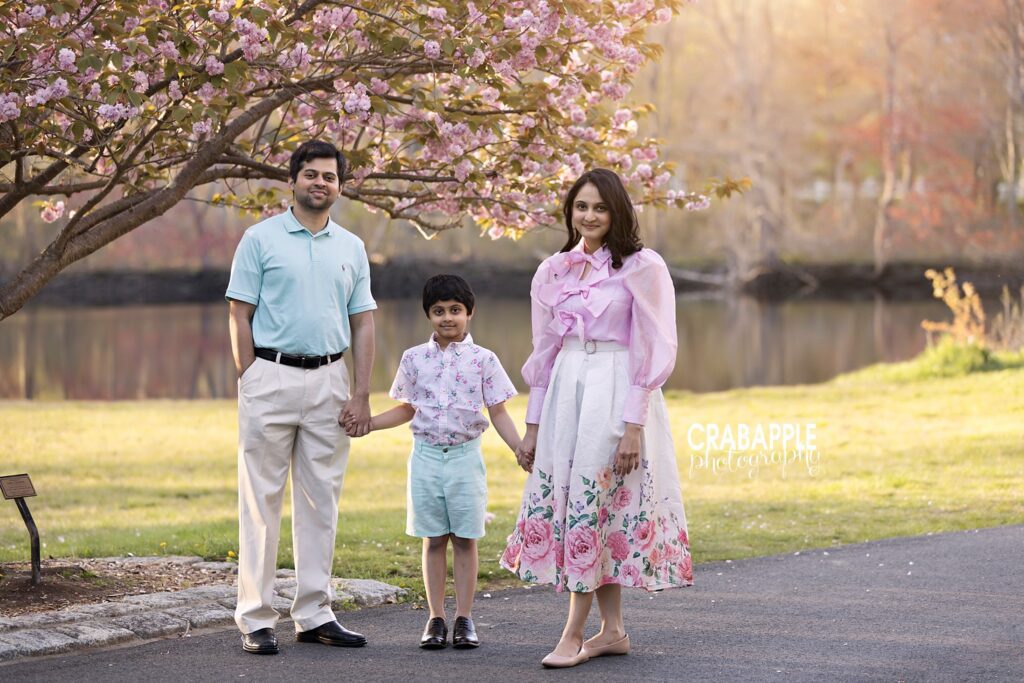 Mom, dad and son stand surrounded by early spring blooms during outdoor family photos