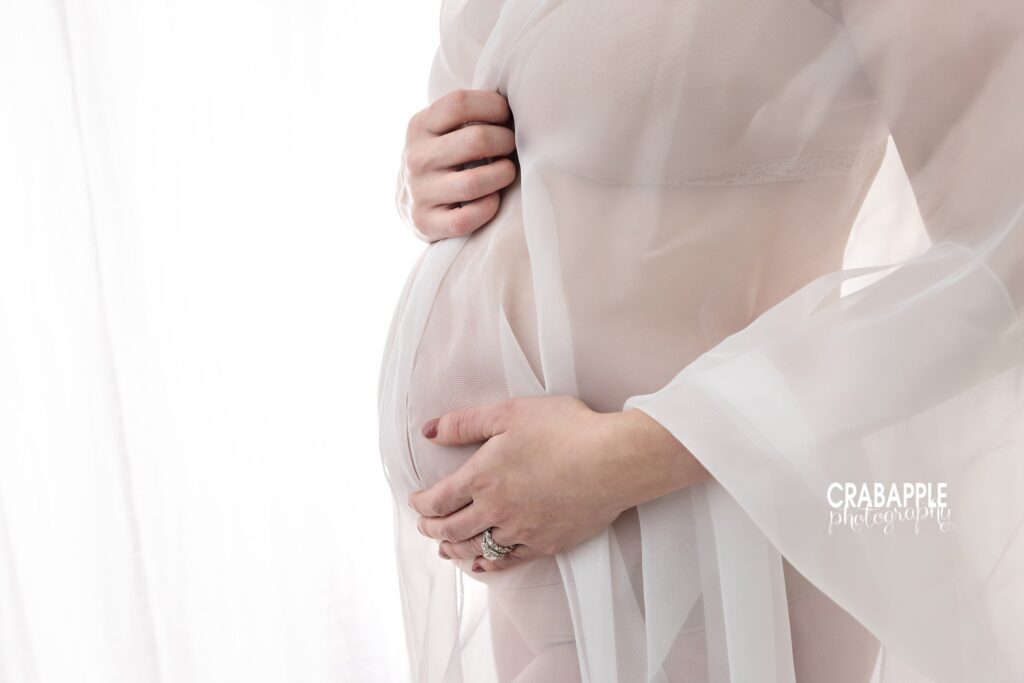 Close-up maternity belly Close-up maternity portrait highlighting an expecting mother's belly while wearing a sheer white robe