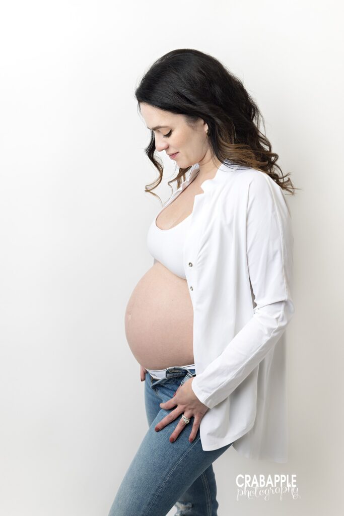 Casual studio maternity portrait Chic maternity portrait of an expecting mother wearing jeans and a white top in the studio