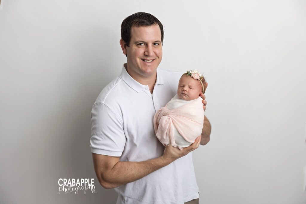 Dad gently holding his newborn baby girl during an in-studio newborn photography session
