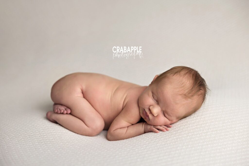 Newborn baby girl sleeping on her belly in a simple, softly lit portrait
