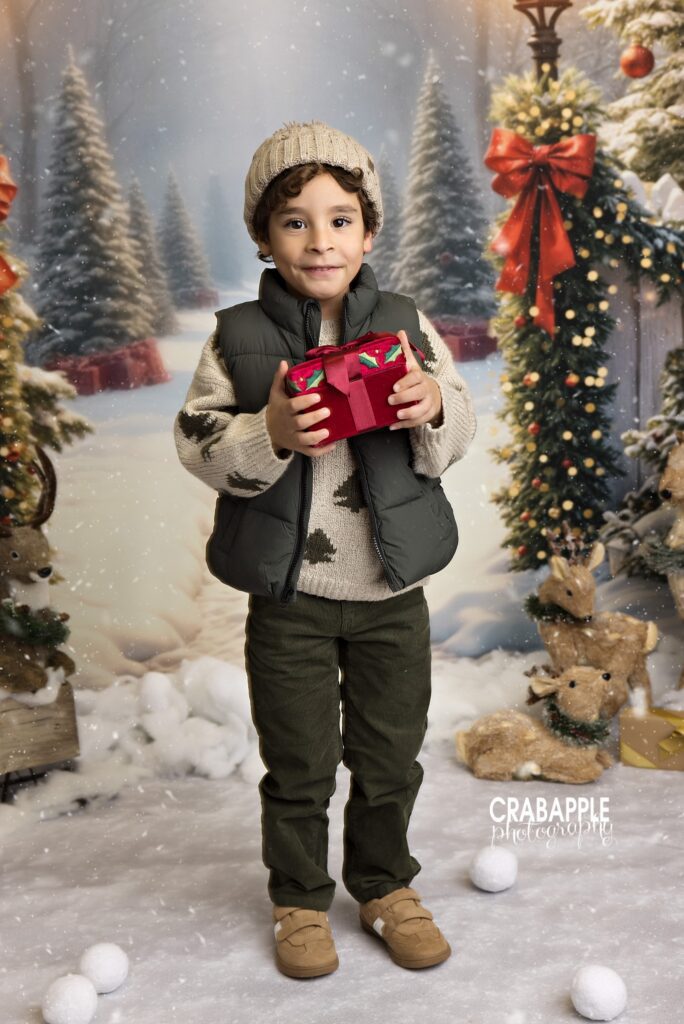 Child holding a wrapped present in a winter-themed Christmas portrait session	