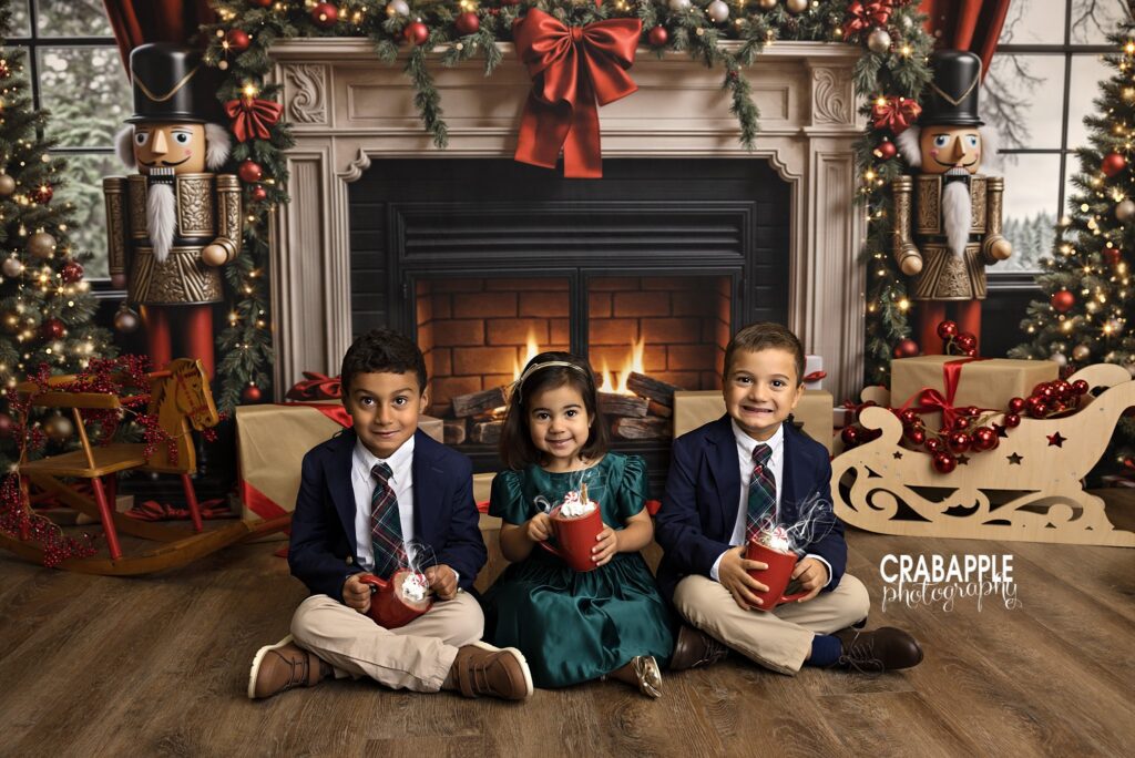 Siblings sitting together in front of a decorated Christmas fireplace during a holiday mini session	