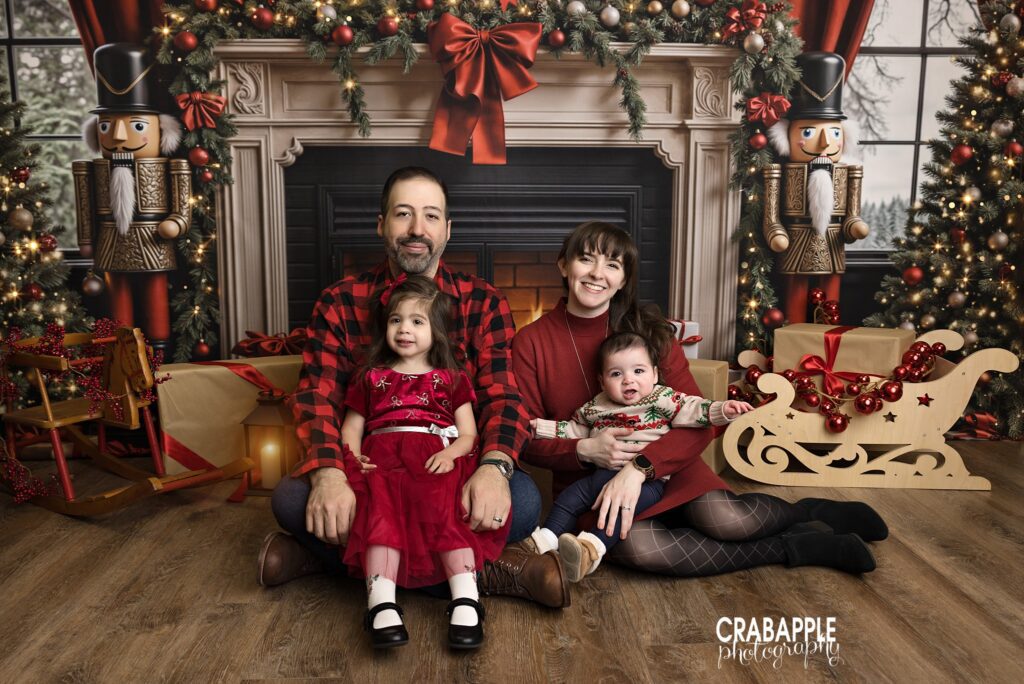 Family portrait in a cozy Christmas living room set with a decorated fireplace and holiday greenery	