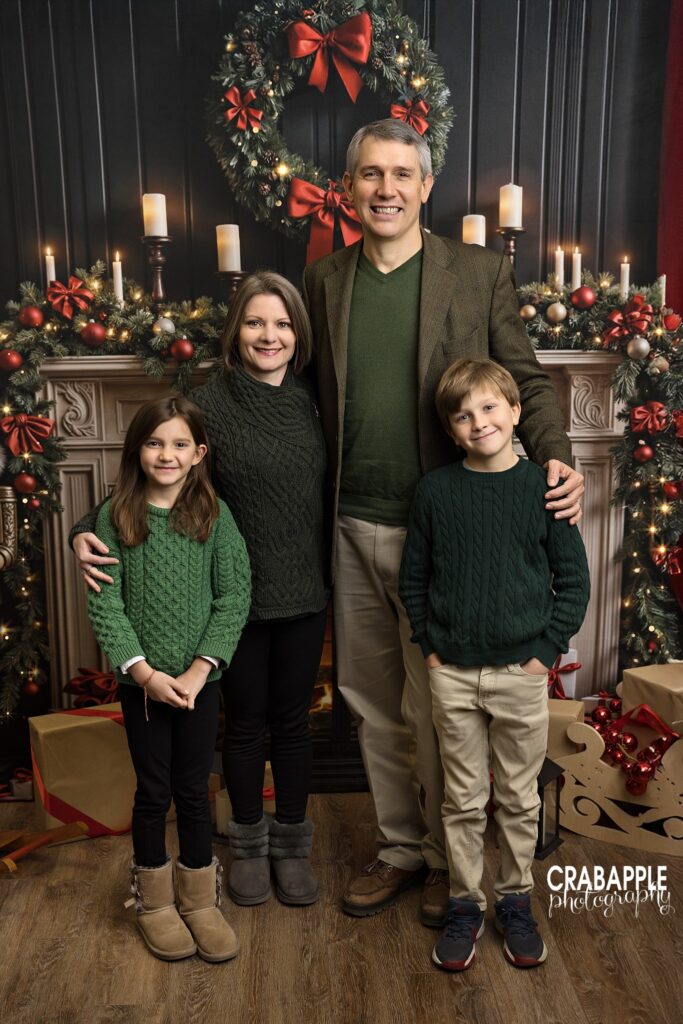 Family posing together in front of a festive living room set during a Christmas mini session in Andover, MA	
