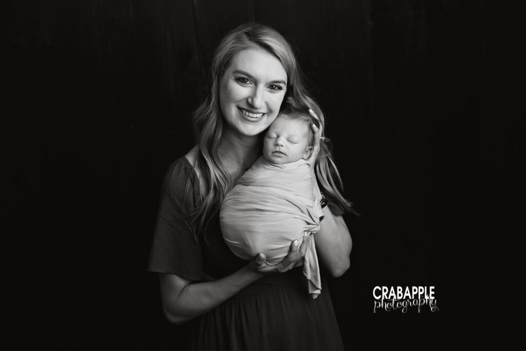 Newborn baby boy cuddled close to his mother in a black and white portrait
