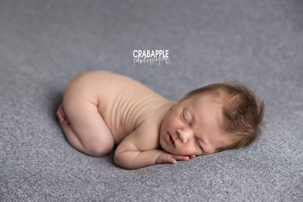 Newborn baby boy posed with his bottom in the air on a gray blanket
