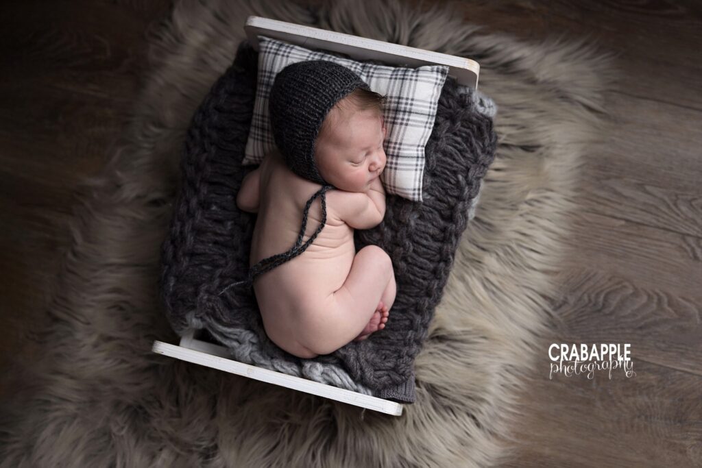 Newborn baby boy sleeping on a small wooden bed in a classic studio portrait
