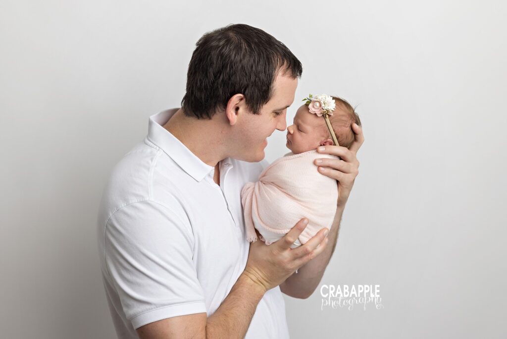 Father holding his newborn daughter close for a sweet nose-to-nose moment

