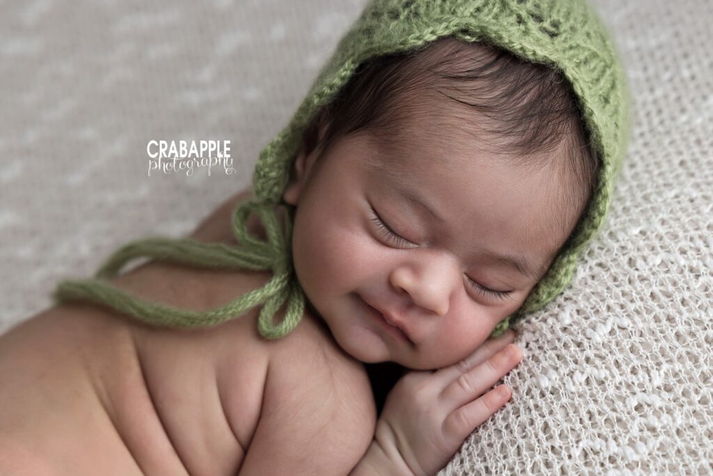 Close-up portrait of a newborn girl wearing a light green knit bonnet	